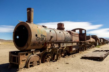 Uyuni paslı tren mezarlığı. Tren mezarlığı. Eski terk edilmiş trenler ve tekerlekler çölün ortasında kumlara kurulur. Uyuni 'deki manzara manzarası. Bolivya 'da Turist Çekimi. Güney Amerika Doğası