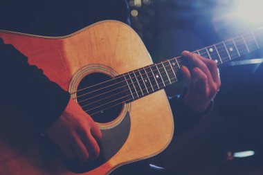 Gitar elinde. Gitar çalan, elinde akustik gitar tutan bir adam. Gitar çal. Müzik konsepti. Koronavirüs nedeniyle karantina ve tecrit süresince izleyiciler için canlı yayında izleyiciler bekliyor