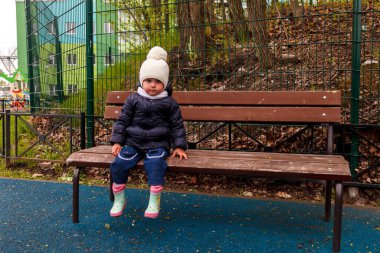 Çocuk kapalı oyun bahçesinde. Kapalı alanda motosikletli üzgün bir kız. Oyun alanı uyarı bandıyla kapatıldı. Genç kız Covid 19 salgını sırasında kapalı oyun parkına bakıyor.