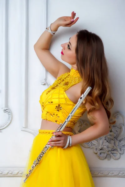 Female in yellow dress with flute on white background. Flute in hand. Stylish girl with musical instrument. For magazine cover, website. Author\'s space. Large background space for inscription or logo
