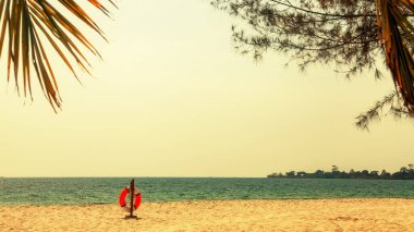Boş tropik plaj arka planı. Ufuk, gökyüzü ve beyaz kum. Plaj manzarası. Plaj afişi için can simidi ve palmiye yapraklarıyla yaz manzarası. Yazarın yeri. Yazı veya logo için geniş boşluk