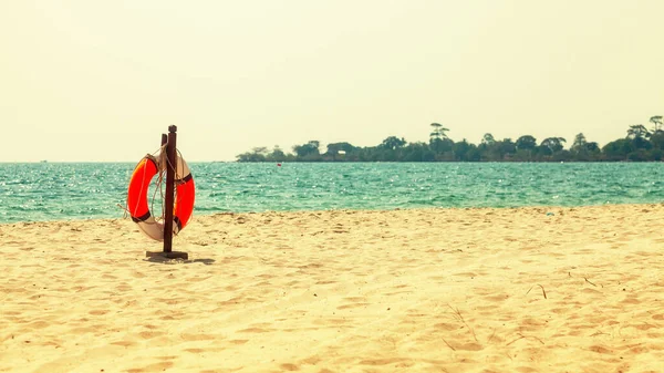Boş tropik plaj arka planı. Ufuk, gökyüzü ve beyaz kum. Plaj manzarası. Plaj afişi için can simidi ve palmiye yapraklarıyla yaz manzarası. Yazarın yeri. Yazı veya logo için geniş boşluk