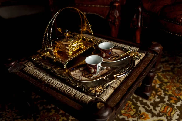 トレイの上のティーカップと砂糖ボウルは 古い小さなテーブルの上に立つ ヴィンテージ風のお茶セット 古いセラミックティーセットと金の箱 茶道の概念 碑文やロゴのための大きなスペース — ストック写真