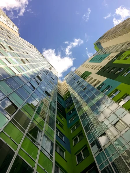Modern building. View from bottom up. Skyscraper reaches for clouds. Green glass house against blue sky. Author\'s space. Large background space for an inscription or logo