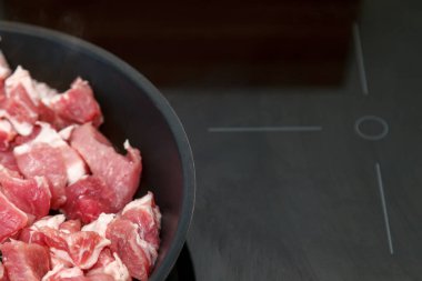 Çiğ et parçaları yakın plan, arka planda çiğ domuz eti evde yağlı et pişiriyor. Tavada pişmiş yemek. Çok şişman. Lezzetli et ürünleri kızartması. Kırsal tarzda pişirme güveci, üst Görünüm