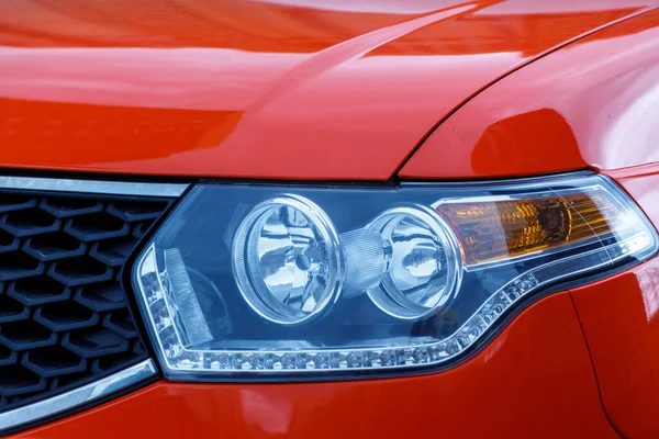 Headlight of red car. Modern car headlight close-up. Stylish and unusual car headlight for road lighting. Photorealistic rendering, universal design, non-brand. Concept auto shows. Auto design