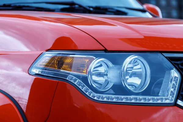 Headlight of red car. Modern car headlight close-up. Stylish and unusual car headlight for road lighting. Photorealistic rendering, universal design, non-brand. Concept auto shows. Auto design
