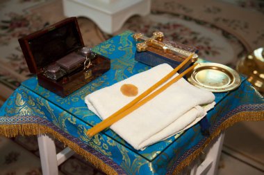 Ortodoks kilisesi. Mumlar, haç, ikon, dua kitabı, masada İncil. Tapınakta merasim için eşyalar. Kutsal suda yeni doğmuş bir çocuğun vaftiz törenine hazırlanıyorum. Vaftiz töreni.