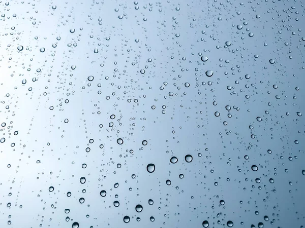 Arka plandaki su damlaları. Doğal yağmur damlaları. Pencere camlarına yağmur damlası. Camdaki yağmur damlalarının soyut bir görüntüsü. Soyut yağmur damlası cam üzerine yağar. Bir yazı veya logo için yer