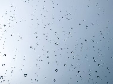 Arka plandaki su damlaları. Doğal yağmur damlaları. Pencere camlarına yağmur damlası. Camdaki yağmur damlalarının soyut bir görüntüsü. Soyut yağmur damlası cam üzerine yağar. Bir yazı veya logo için yer