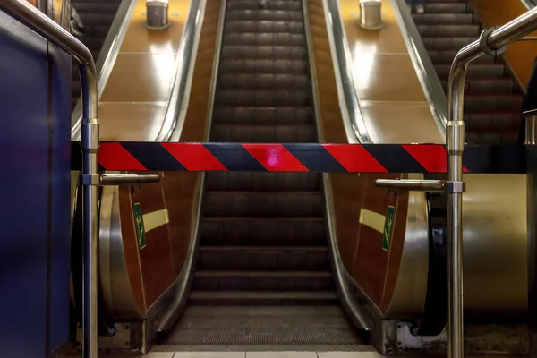 Closed escalator in metro. Bottom view. Repair of escalators, no entrance, closed passage. Red and black stripes on forbidding barrier. Escalator stopped. Space for your label and advertising