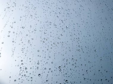 Arka plandaki su damlaları. Doğal yağmur damlaları. Pencere camlarına yağmur damlası. Camdaki yağmur damlalarının soyut bir görüntüsü. Soyut yağmur damlası cam üzerine yağar. Bir yazı veya logo için yer