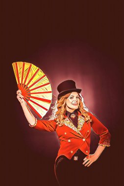 Sahne kostümlü ve kafasında silindir şapka olan bir kız. Tiyatro kıyafeti giyen bir illüzyonist olan kadın sihirbaz, siyah arka planda sirk hayranını başının üstünde tutuyor. Tiyatro performansı kavramı