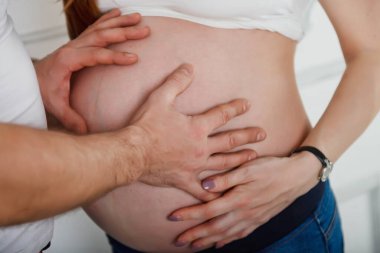 Erkek, ışık duvarına yaslanıp karnına dokunan ikizlere hamile genç karısına sarılır. Kadın ve erkek ellerini karnının üstüne koy. İkizleri Bekleme Konsepti