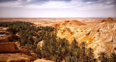 Sahra Çölü 'ndeki Chebika vahasının manzarası. Yerleşim ve avuç içini harap eder. Kuzey Afrika 'daki manzaralı dağ vahası. Yaya olarak Jebel El Negueba 'da bulunuyor. Güneşli bir öğleden sonra Atlas Dağları. Tozeur, Tunus