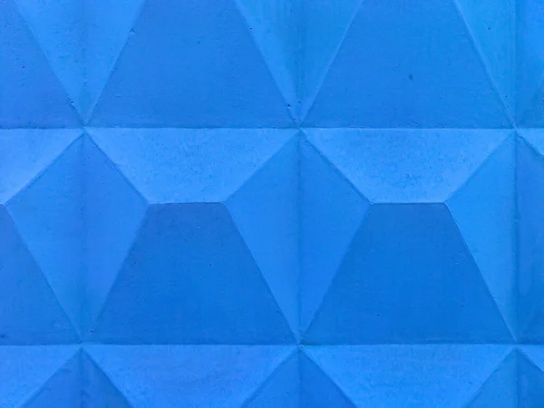 Concrete geometric seamless pattern. Blue wall with geometric shapes. Texture of plastered painted surface in form triangle. Surface with pyramidal pattern and peeling paint. Background for design