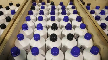 Kimyasal sıvıların depolanması ve depolanması. Ahşap kutularda düz sıra sıvı konteynırlar. Depoda depolanan şişelerin arka planı. Mal depolama ve depolama kavramı