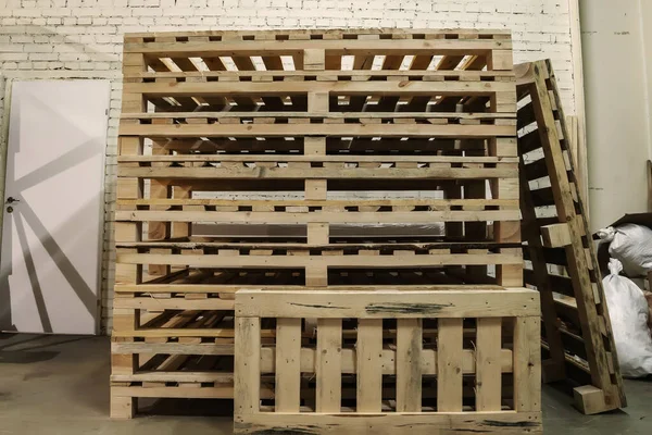 Stacked used wooden pallets in warehouse. Stacks of Euro-type cargo pallets. Background of wooden pallets. Concept of warehousing and storage of goods
