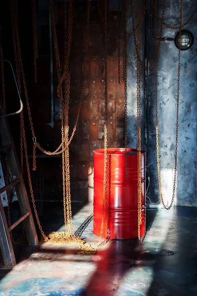 Interior of factory industrial shop with chains and a red barrel is illuminated by sunlight from window. Luxury background for presentation, design, poster with copyright space for text or logo