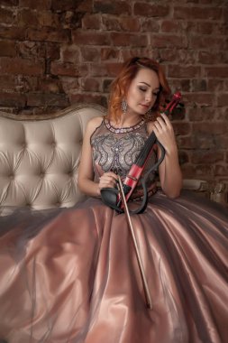 Güzel, kemanı olan ince bir kadın. Sahne görüntüsü retro kostümlü bir kadın. İç dokuma odasında oturan elbiseli bir kızın duyguları. Aktris yeteneklerini gösteriyor. Fotoğrafta yazar alanı