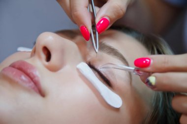 Güzellik salonundaki güzel genç bayana kirpik uzatma işlemi. İçişleri salonundaki müşteri hizmetleri inanılmaz bir imaj yaratıyor. Makyaj yaratma sihirbazı. Tarz kavramı, güzellik tatmini
