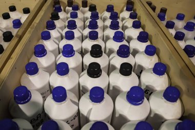 Kimyasal sıvıların depolanması ve depolanması. Ahşap kutularda düz sıra sıvı konteynırlar. Depoda depolanan şişelerin arka planı. Mal depolama ve depolama kavramı