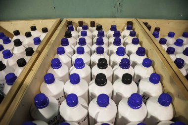 Kimyasal sıvıların depolanması ve depolanması. Ahşap kutularda düz sıra sıvı konteynırlar. Depoda depolanan şişelerin arka planı. Mal depolama ve depolama kavramı