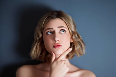 Koyu arka planda Slav görünümlü genç ve güzel bir kadın modelin yakın çekimi. Düşünüyor ve başka tarafa bakıyor. Yansıma ve ilham kavramı. Telif Hakkı Boşluğu