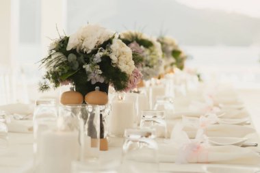 Denizin arka planında temiz havayla süslenmiş düğün masası. Tatil ve akşam yemeği için çiçek masa süslemeleri. Tatil, etkinlik, parti ya da açık hava restoranında verilen resepsiyon. Site için pankart