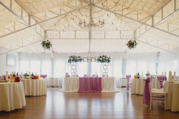 Covered hall for wedding receptions with tables and floral decorations. Celebration restaurant for newlyweds and guests. Amazing designed interior. Luxury design for events. Copyright space for site