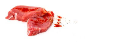 Beyaz arka planda taze çiğ biftek. Hardallı domuz pirzolası ve kırmızı Cayenne biberi pişirmeye hazır. İki parça et. Mutfak becerisi kavramı. Bir yazı veya logo için yer