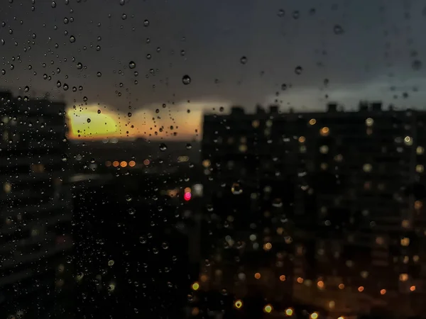 背景水滴 窗玻璃上的雨滴 天然的雨滴模式 玻璃上的雨滴的抽象镜头 夜晚的城市和窗外的日落 有选择的重点 文字或标志的空间 — 图库照片