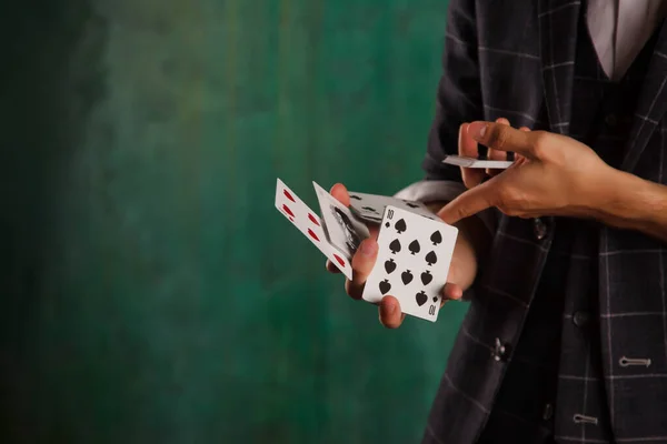 ギャンブルカードを持つ若い男のクローズアップ肖像画 ハンサムな男はトランプでトリックを示しています 緑のテクスチャの背景に魔術師の巧妙な手 エンターテインメントと趣味の概念 著作権空間 — ストック写真