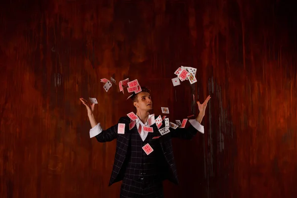 ギャンブルカードを持つ若い男のクローズアップ肖像画 ハンサムな男はトランプでトリックを示しています 茶色のテクスチャの背景に魔術師の巧妙な手 エンターテインメントと趣味の概念 著作権空間 — ストック写真