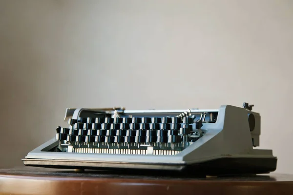 旧的经典复古打字机在尘土飞扬的办公桌上 衬托着米色的墙壁背景 苏联时代打字机的特写 复制空间 — 图库照片