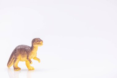 Beyaz arka planda izole edilmiş renkli plastik bir dinozor heykelinin yakın plan görüntüsü.