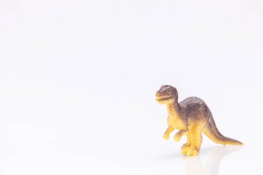 Beyaz arka planda izole edilmiş renkli plastik bir dinozor heykelinin yakın plan görüntüsü.
