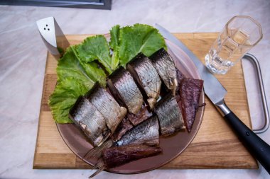 Bir tabak dolusu votkanın yanında salatalık ve tütsülenmiş ringa balığı.