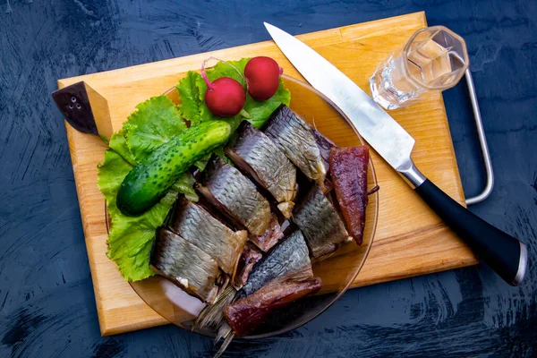 Bir tabak dolusu votkanın yanında salatalık ve tütsülenmiş ringa balığı.