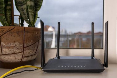 a black Wi-Fi router stands on the windowsill clipart
