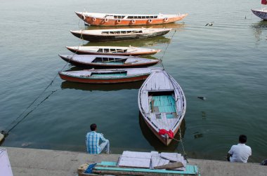 Yerli halk Ganga ghat ve tekne desenleri üzerinde oturuyorlar. Fotoğraf Varanasi Hindistan 'da Munshi ghat yakınlarında çekildi..