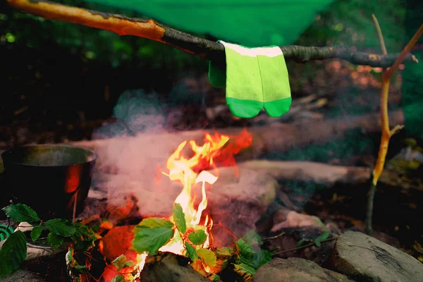 Drying wet socks on the bonfire during camping. Socks drying on fire. Active rest in forest. Adventure