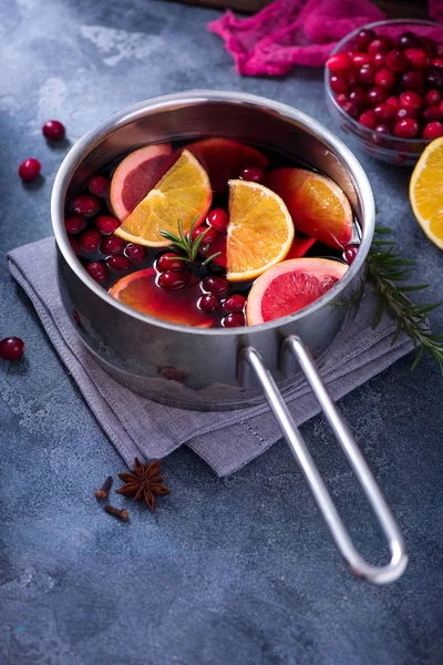 Mulled wine in cooking saucepan with fruits and cranberries, hot winter drink