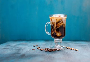 Mavi arka plan kopyalama alanı üzerinde bir bardak buzlu kahve