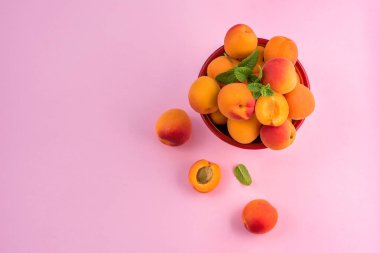 Pembe kağıt arka plan kopyalama alanı üzerinde bir kapta Olgun kayısı