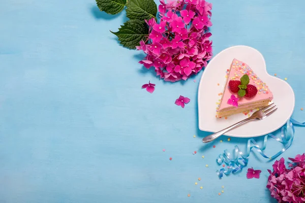 Piece of festive cake with flowers on blue background, flat lay — Stock Photo, Image
