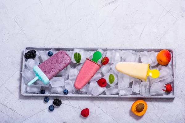 Popsicles ice cream with fruits and berries on copy space backgr