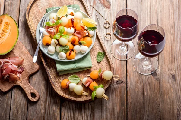 Dvě skleničky červeného vína, melounu, mozzarelly, prosciutto appetizera — Stock fotografie