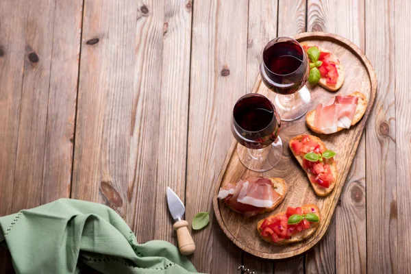 Dvě skleničky červeného vína a bruschetty, předkrmy na dřevěné — Stock fotografie
