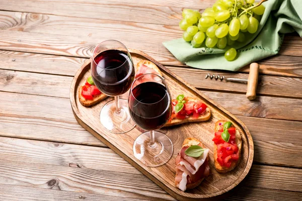 Dos copas de vino tinto, jamón y bruschetta, aperitivo se —  Fotos de Stock
